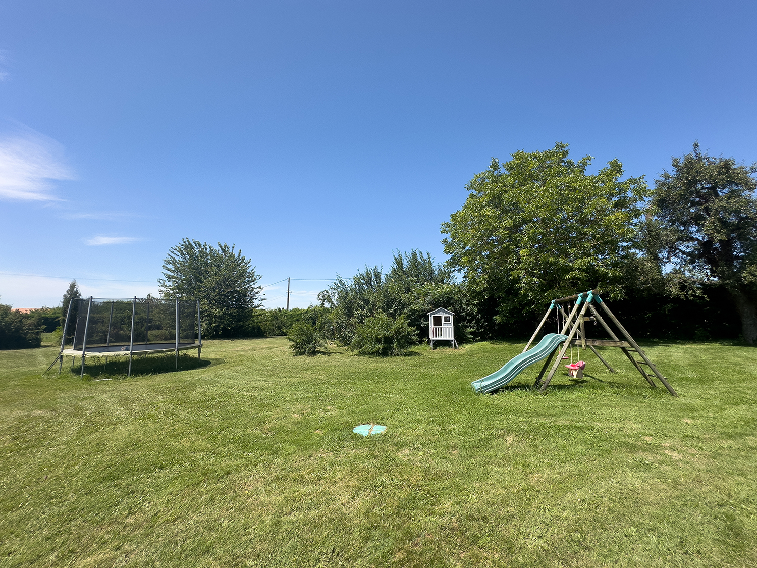 Lawned garden with swings, slide and trampoline